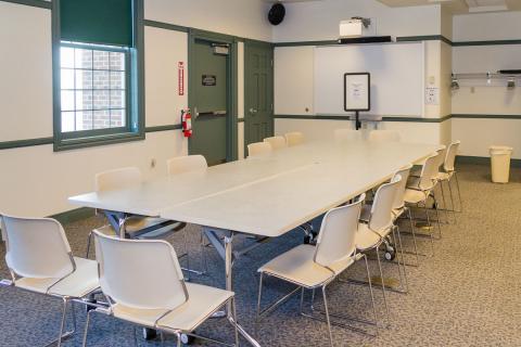 A room with a large table with chairs arranged around it