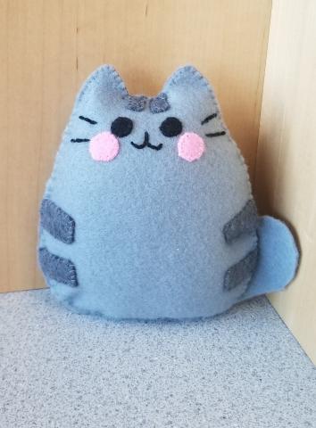 A small gray felt plush of Pusheen the cat- a cute gray cat