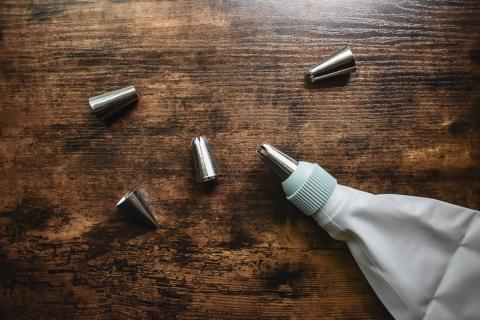 a piping bag and piping tips arranged on a dark wood table