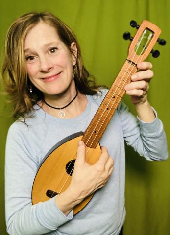 Presenter Julie Stepanek smiling at the camera and holding a ukulele 