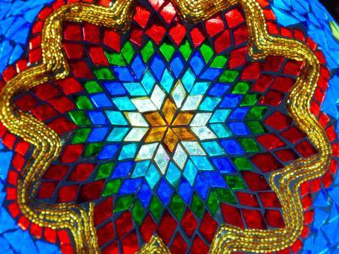 A round pattern of stained glass in blue, green, red, and gold