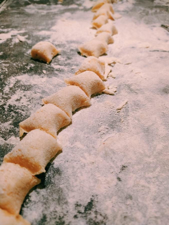 Slightly orange, floured gnocchi in a row on a floured surface