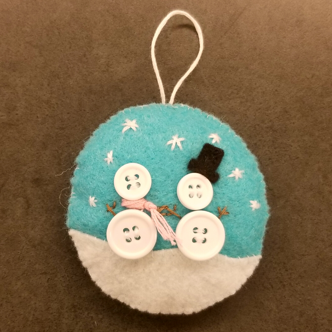 A blue felt circle with button snowmen