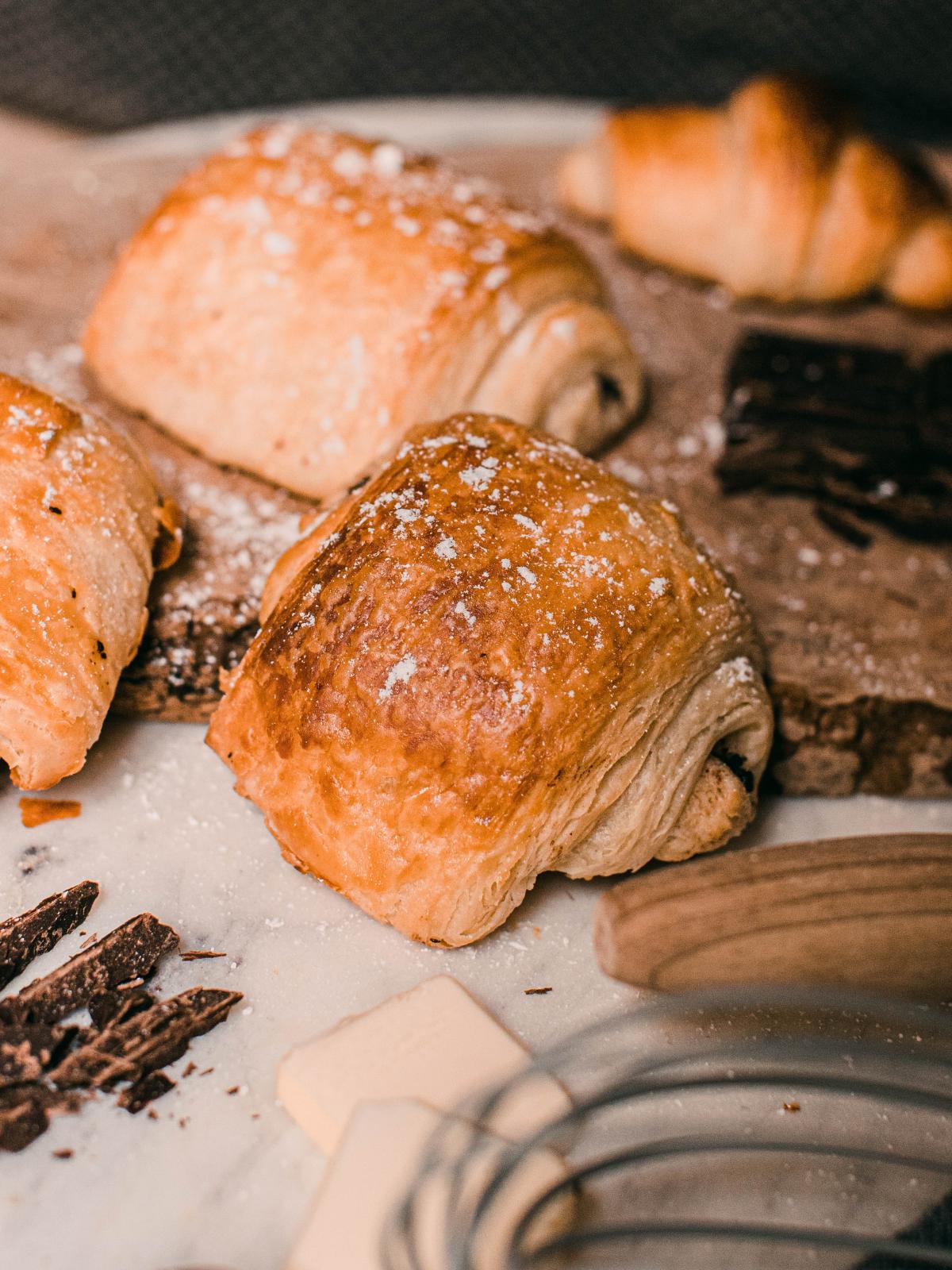 Several small croissants with visible chocolate coming out the sides. The flaky layers and lamination of the croissants are visible.