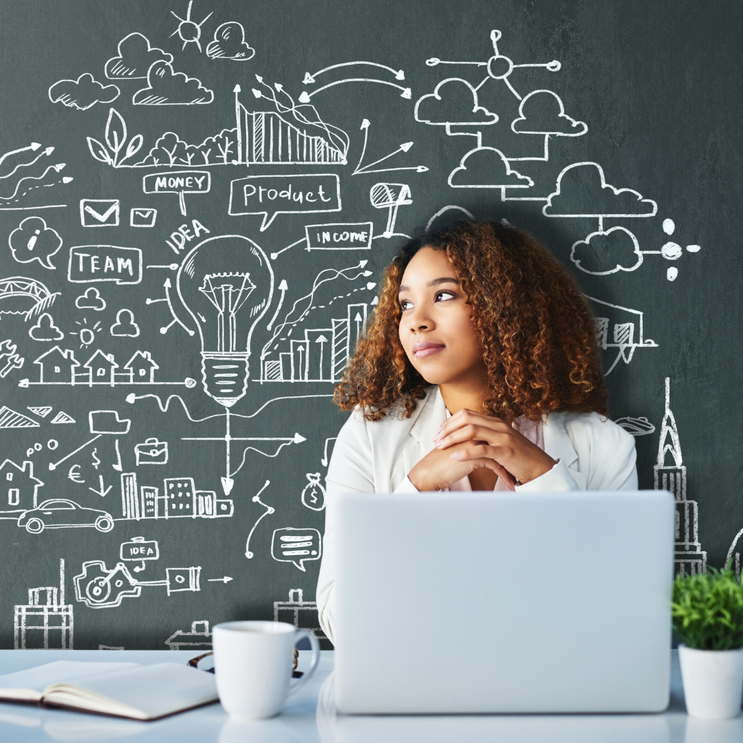 A teenage girl with light brown skin and curly hair sits in front of a computer and looks thoughtfully into the distance, with a sketch of business brainstorming ideas behind her.