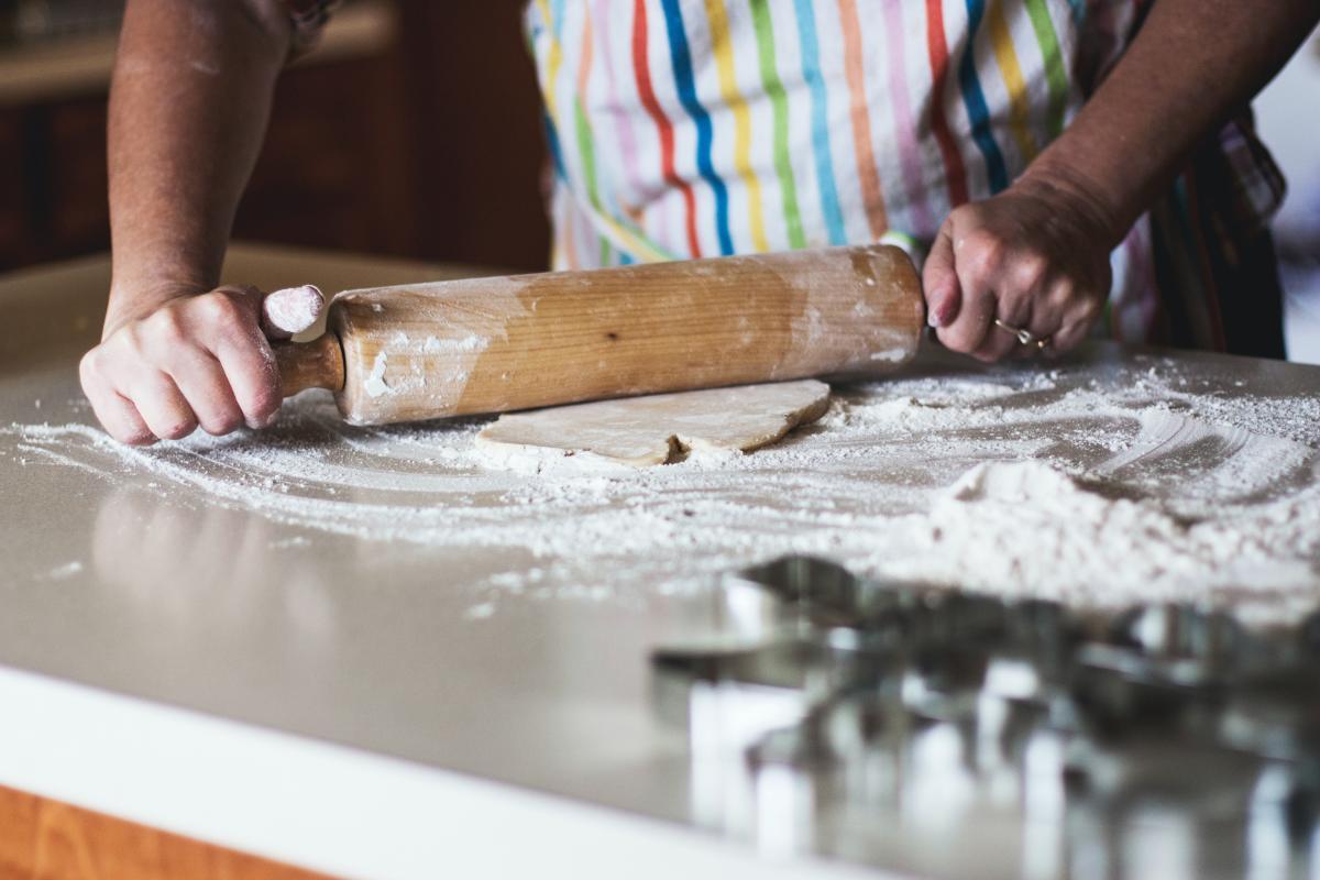 A person in an apron using a rolling pin