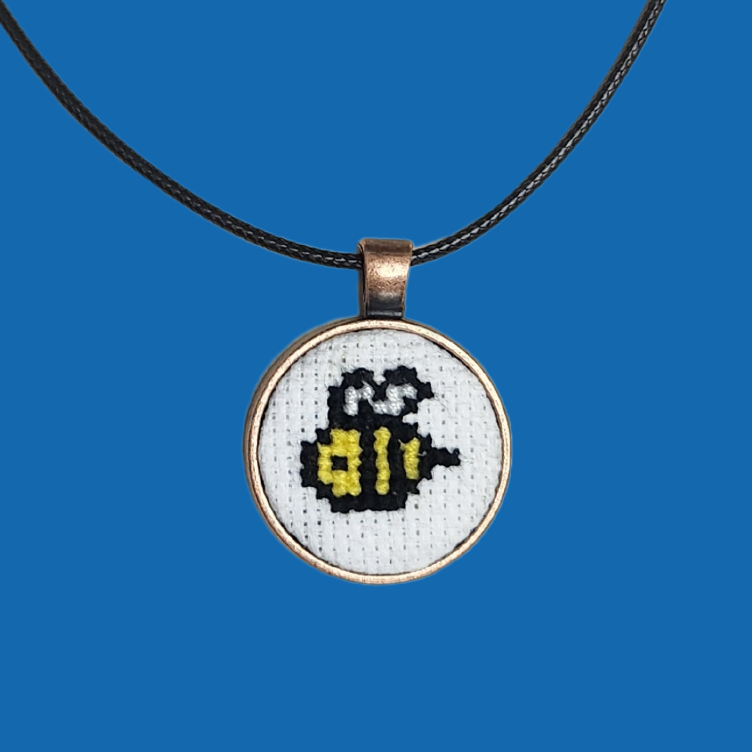 An example of the craft- a small cross stitch bee is on a necklace pendant.